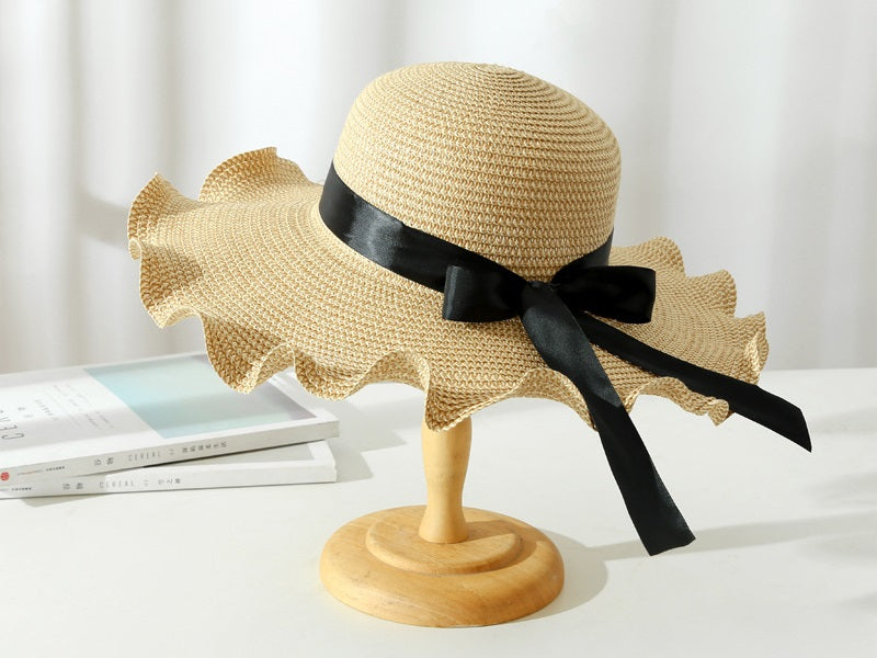 Light brown women's wide brim straw sun hat with floppy derby style, perfect for summer beach and outdoor wear.