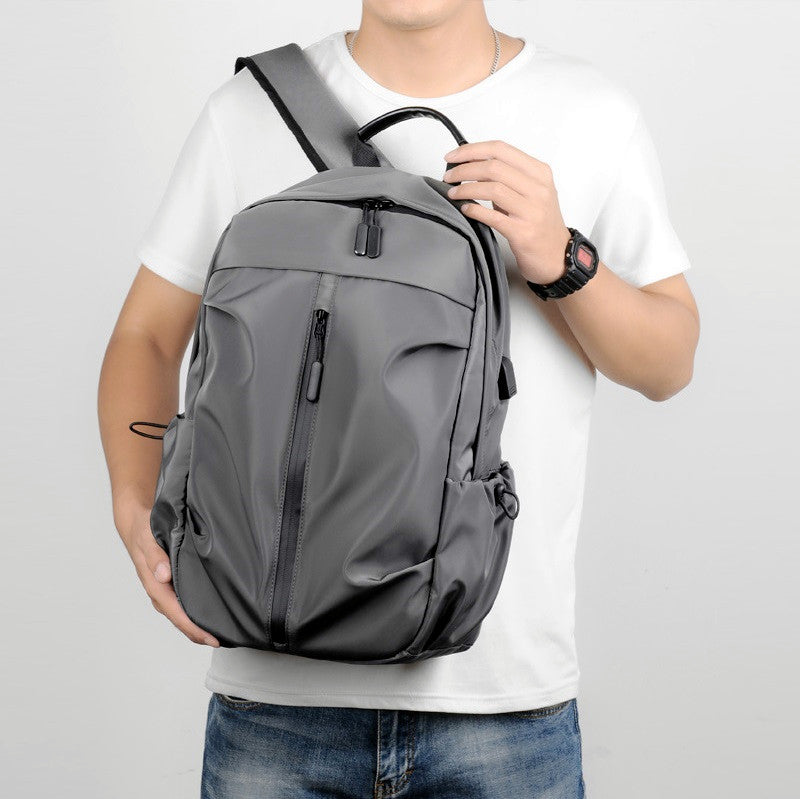 Grey travel backpack with computer compartment, USB charging port, water-resistant design, ideal for commuters and travelers.