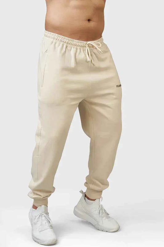 Fuaark Nz Signature Oversized Beige Joggers, soft fabric, relaxed fit, and elastic waistband, displayed on a hanger.