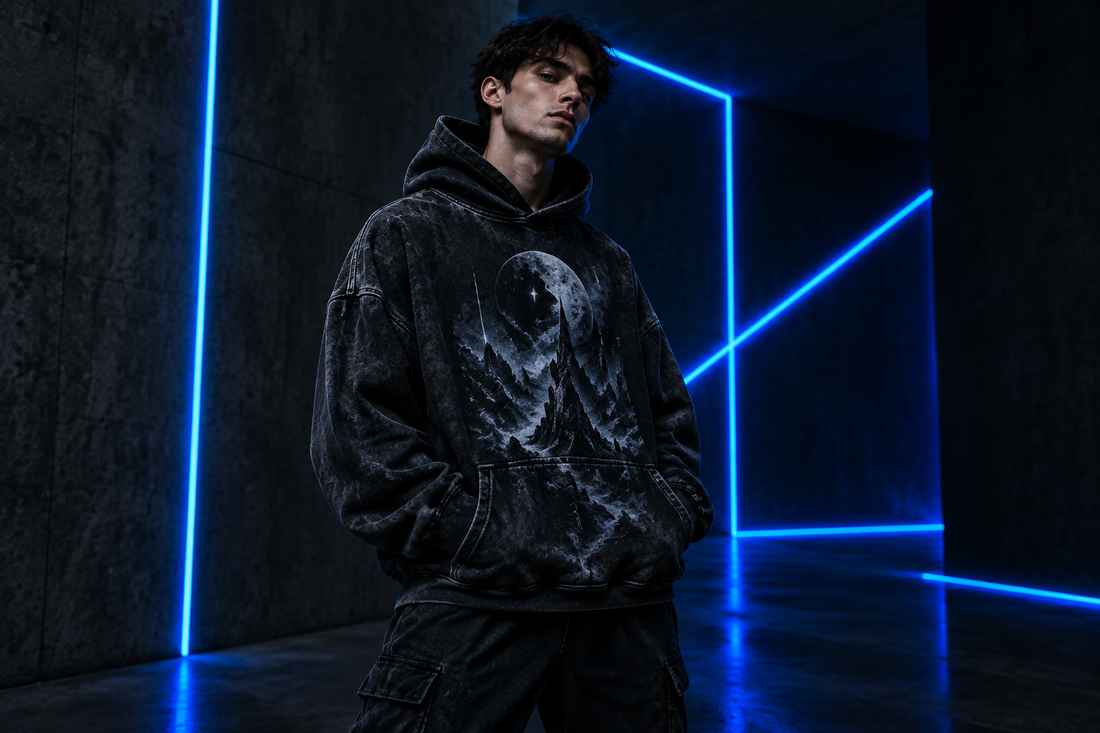 Man wearing an acid-washed black graphic hoodie under electric-blue neon lights