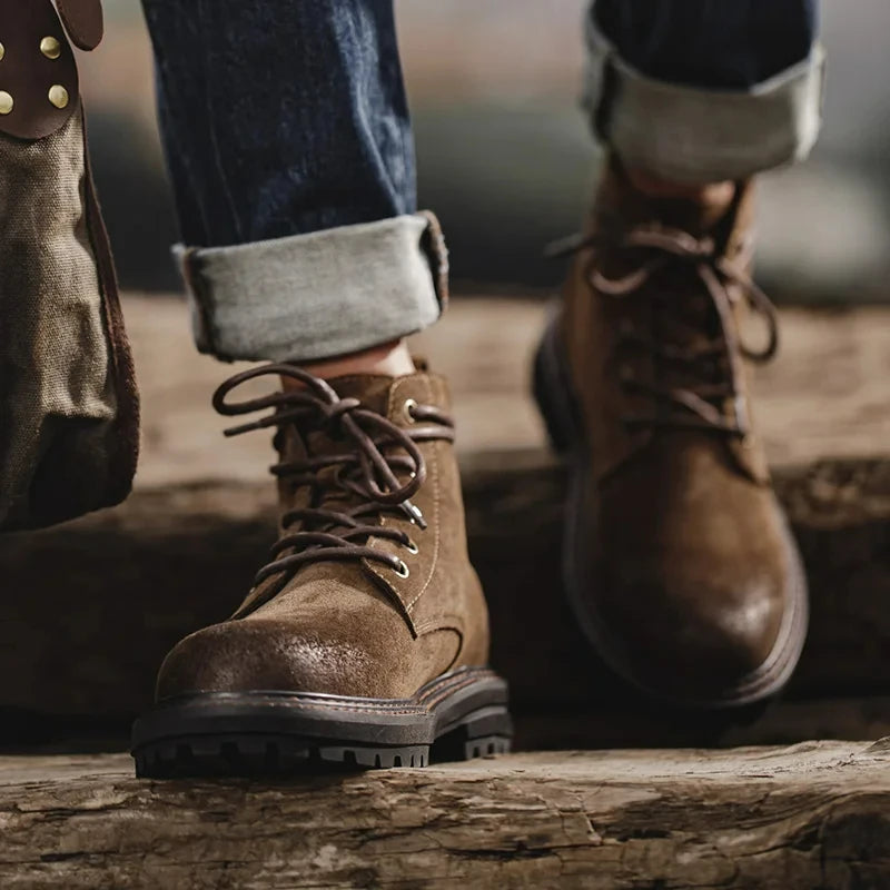 Brown leather boots worn with rolled-up jeans on a wooden surface