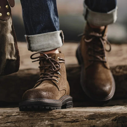 Brown leather boots worn with rolled-up jeans on a wooden surface