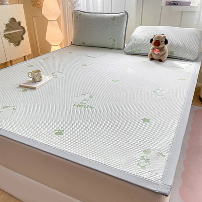 A white mesh mattress cooling pad with a light gray border and green cartoon bunny prints, shown on a bed in a bedroom setting with pillows and a small plush toy.