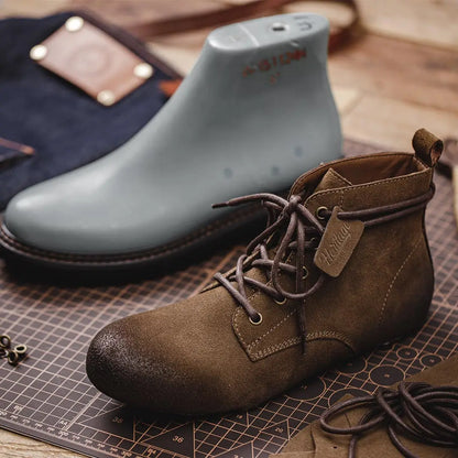 Brown leather boot with laces on a cutting mat, next to a gray shoe and a wallet.