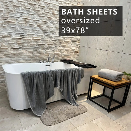 Bathroom scene with oversized bath sheets draped over a bathtub and on a stool.