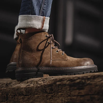 Brown leather boot worn with rolled-up jeans on a dark background