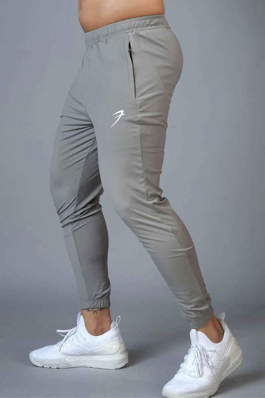 Light grey Fuaark Nz Identity Nylon Joggers with a relaxed fit and adjustable waistband, made of lightweight nylon fabric.