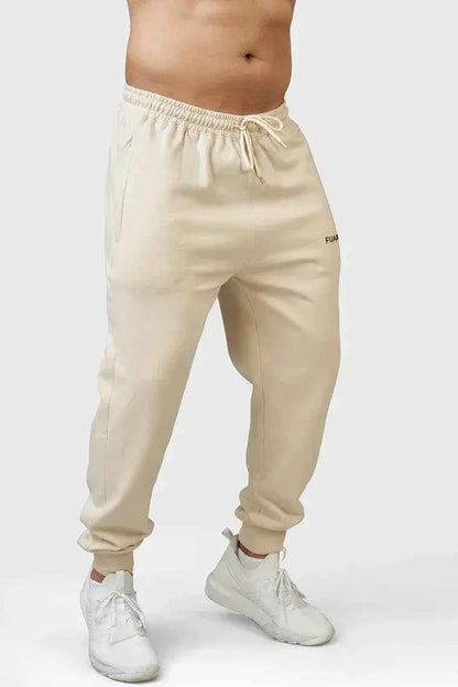 Fuaark Nz Signature Oversized Beige Joggers, soft fabric, relaxed fit, and elastic waistband, displayed on a hanger.
