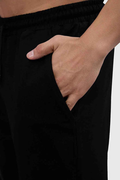 Black Phantom Straight Tracks Track Pants by Fuaark Nz displayed on a hanger with a close-up of fabric and design details.