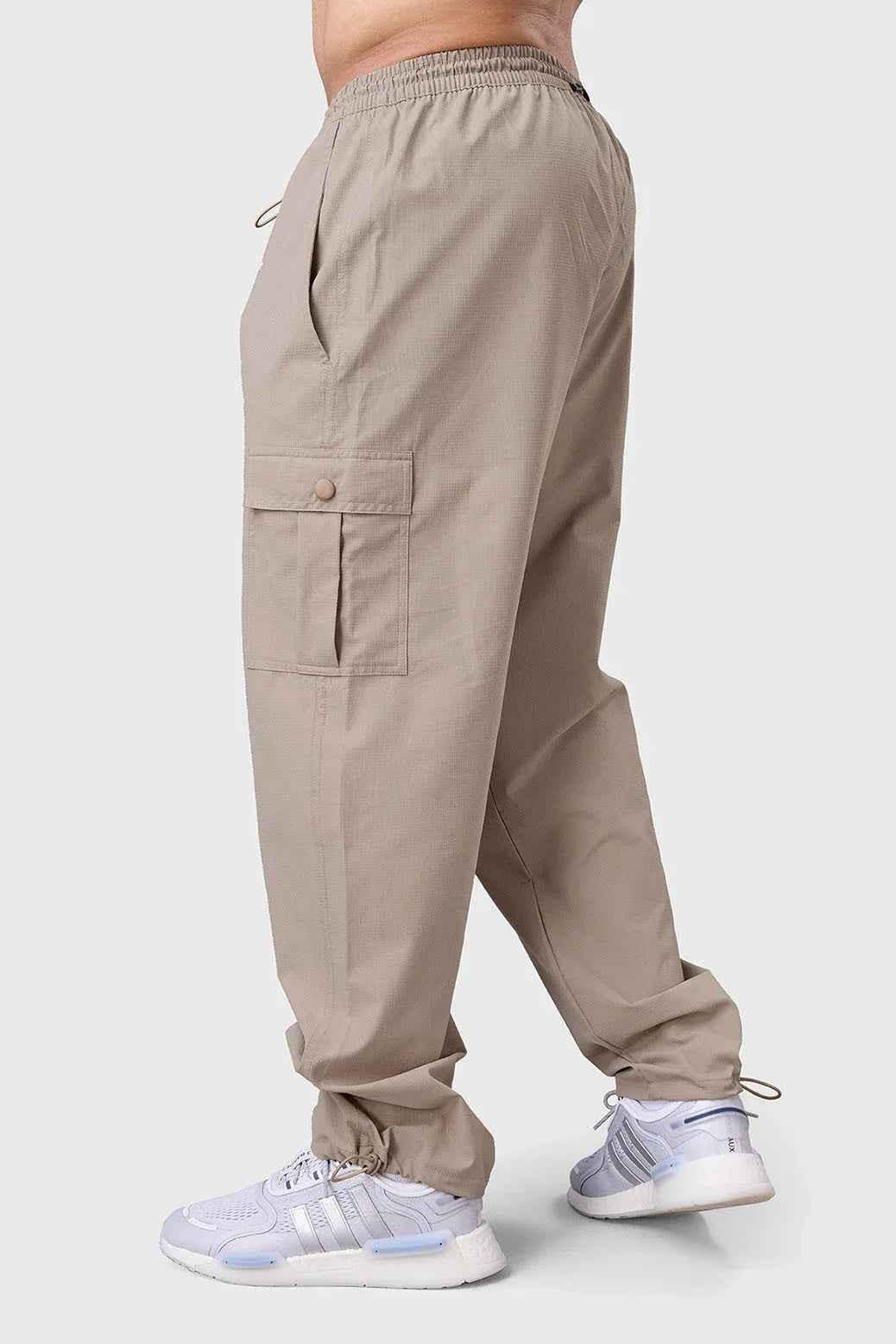 Fuaark NZ beige carpenter cargo track pants with multiple pockets and relaxed fit, shown on a model.