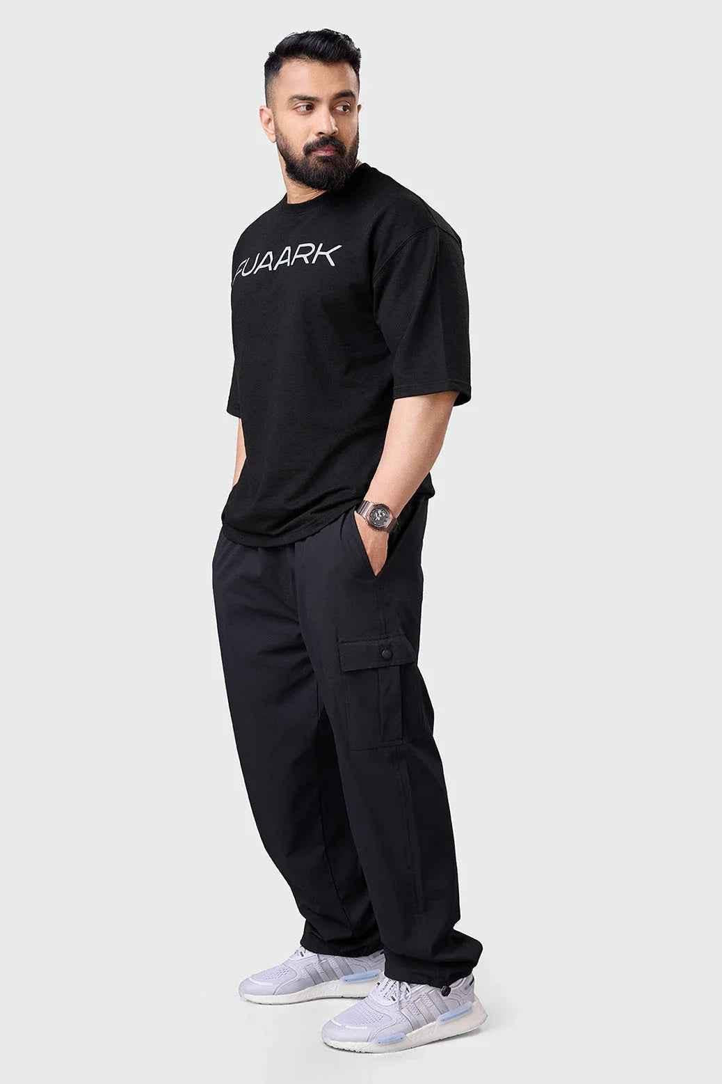 Black Fuaark Nz carpenter cargo track pants displayed on a model, featuring multiple utility pockets and a relaxed fit.