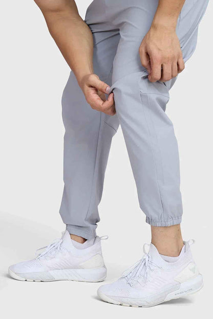Light grey Fuaark Nz Essential Joggers track pants, featuring a comfortable fit and casual style, shown on a model.