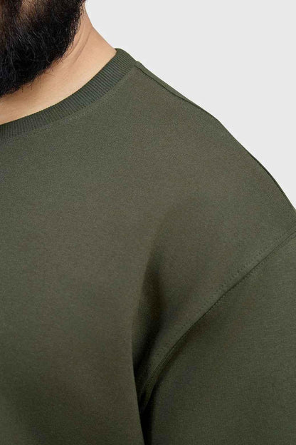 Oversized olive T-shirt from Fuaark Nz, casual fit, soft fabric, displayed on a hanger with a neutral background.