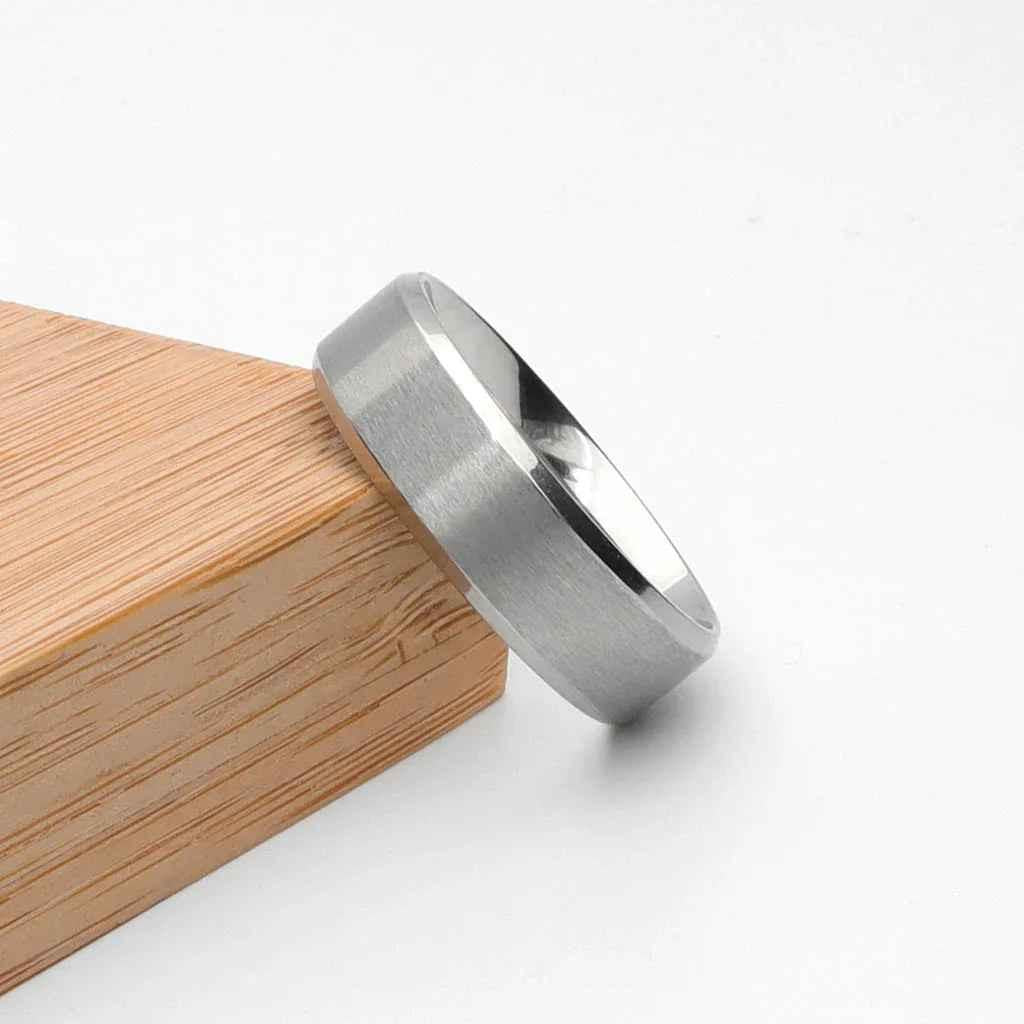 Stainless steel 8mm wide beveled edge band ring by Glitters, featuring a sleek, polished design and smooth beveled edges.