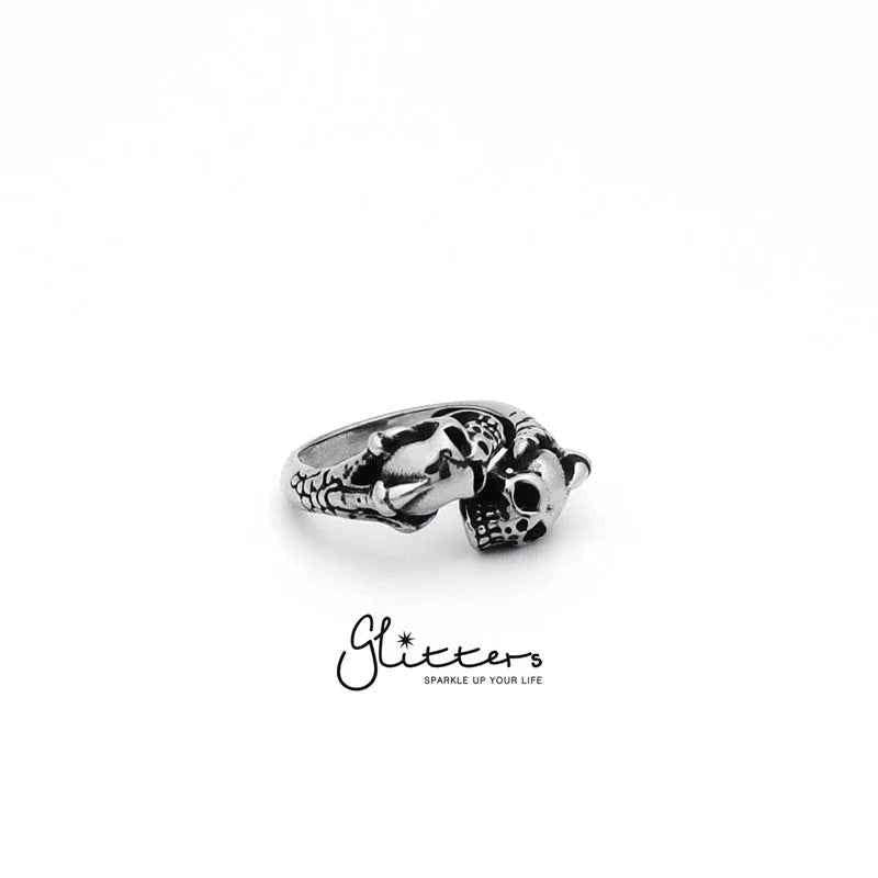 Stainless steel ring by Glitters featuring two skull heads with a dragon claw design, detailed and bold jewelry accessory.